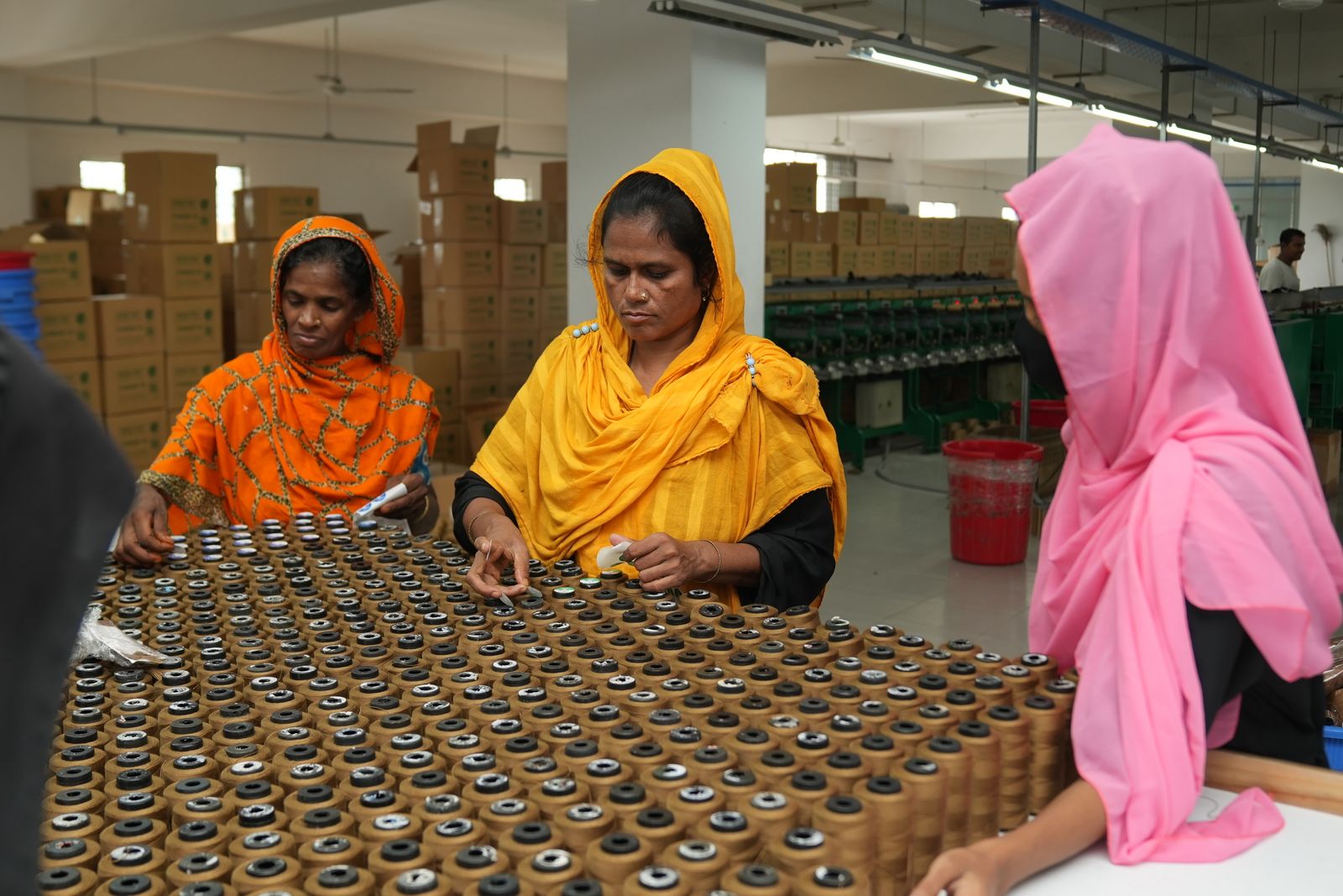Bangladeshi women working together sorting thread spools in a textile factory