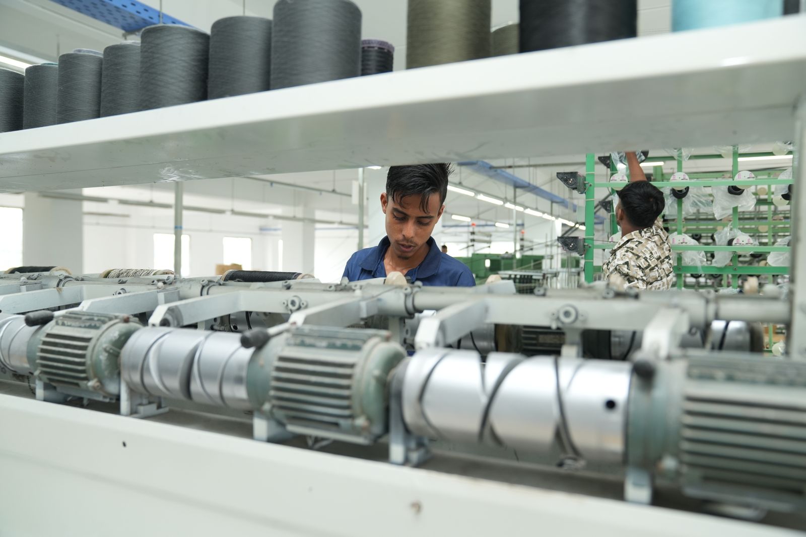 Bangladeshi workers operating yarn machines in a textile factory